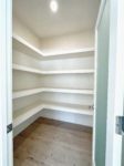 An empty pantry with shelving and frosted door.
