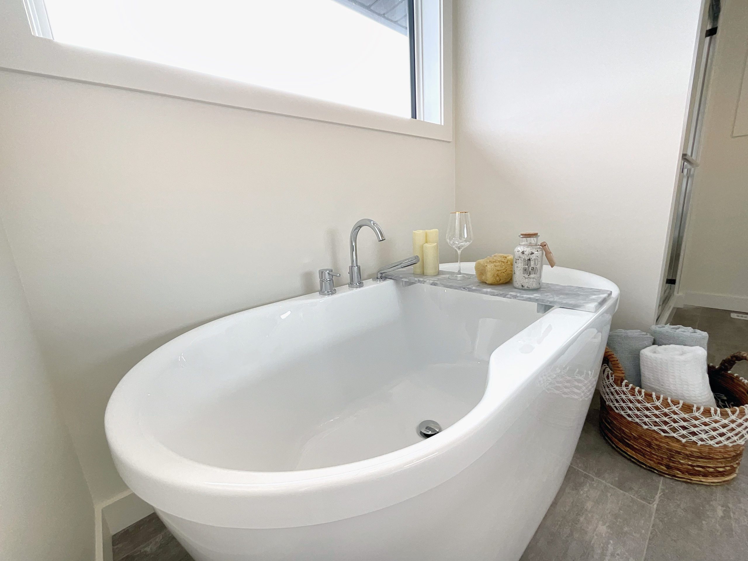 A white freestanding bath tub sitting next to a window.