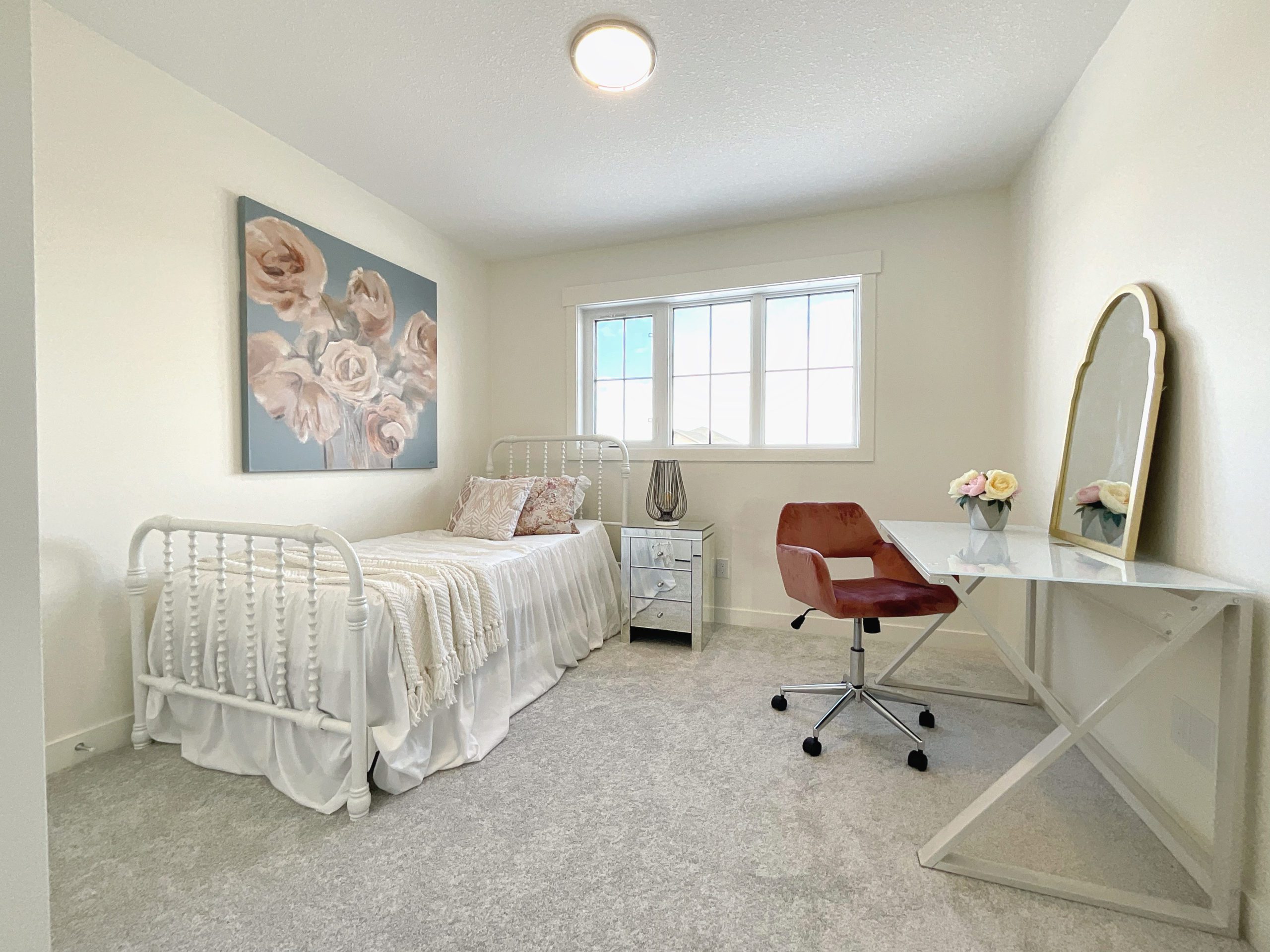 A bedroom with a twin bed, desk and mirror.