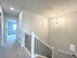 Shows stairwell to main level with railing and chandelier hanging above.