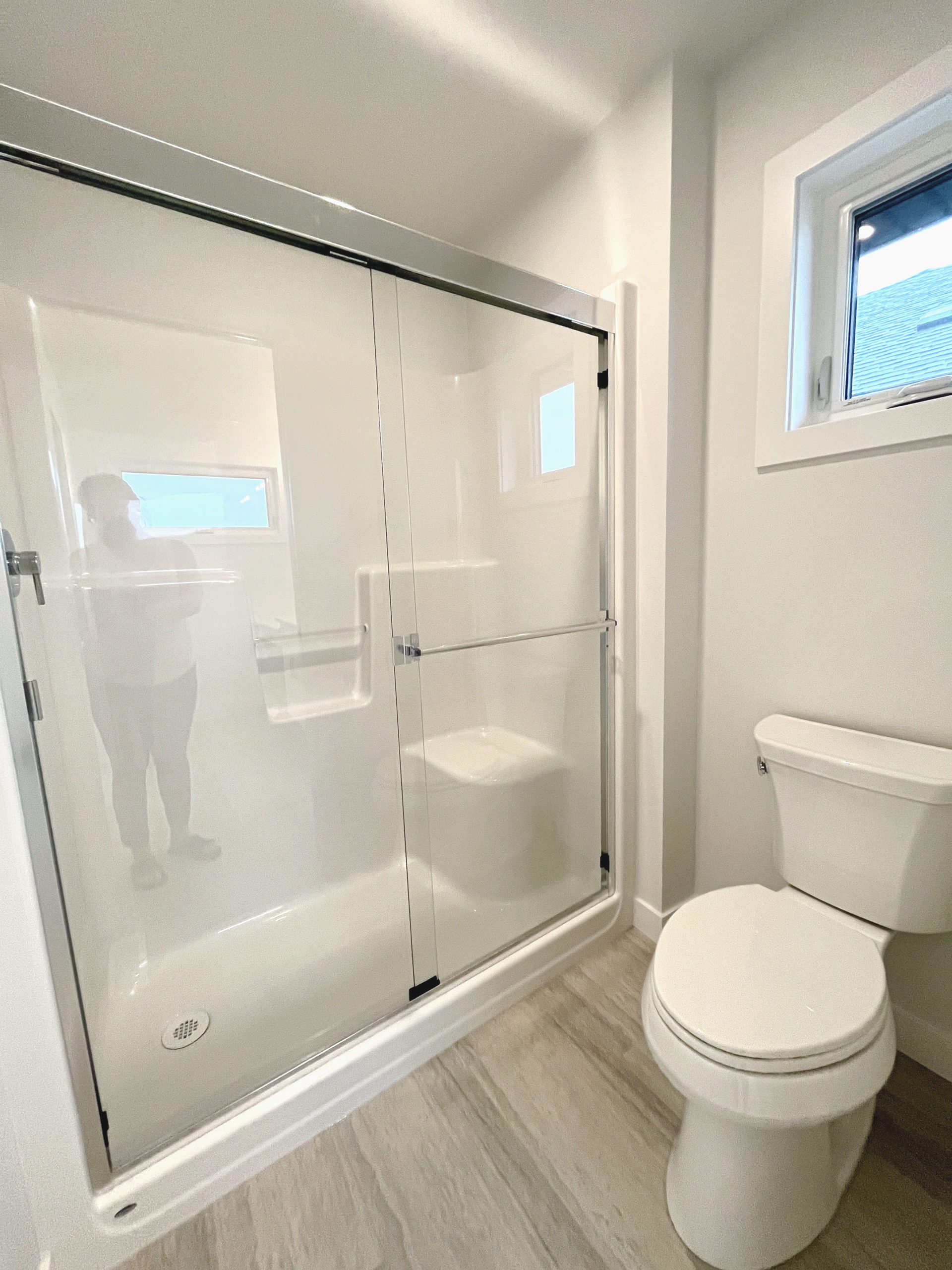 Primary water closet with white toilet sitting next to a walk in shower.