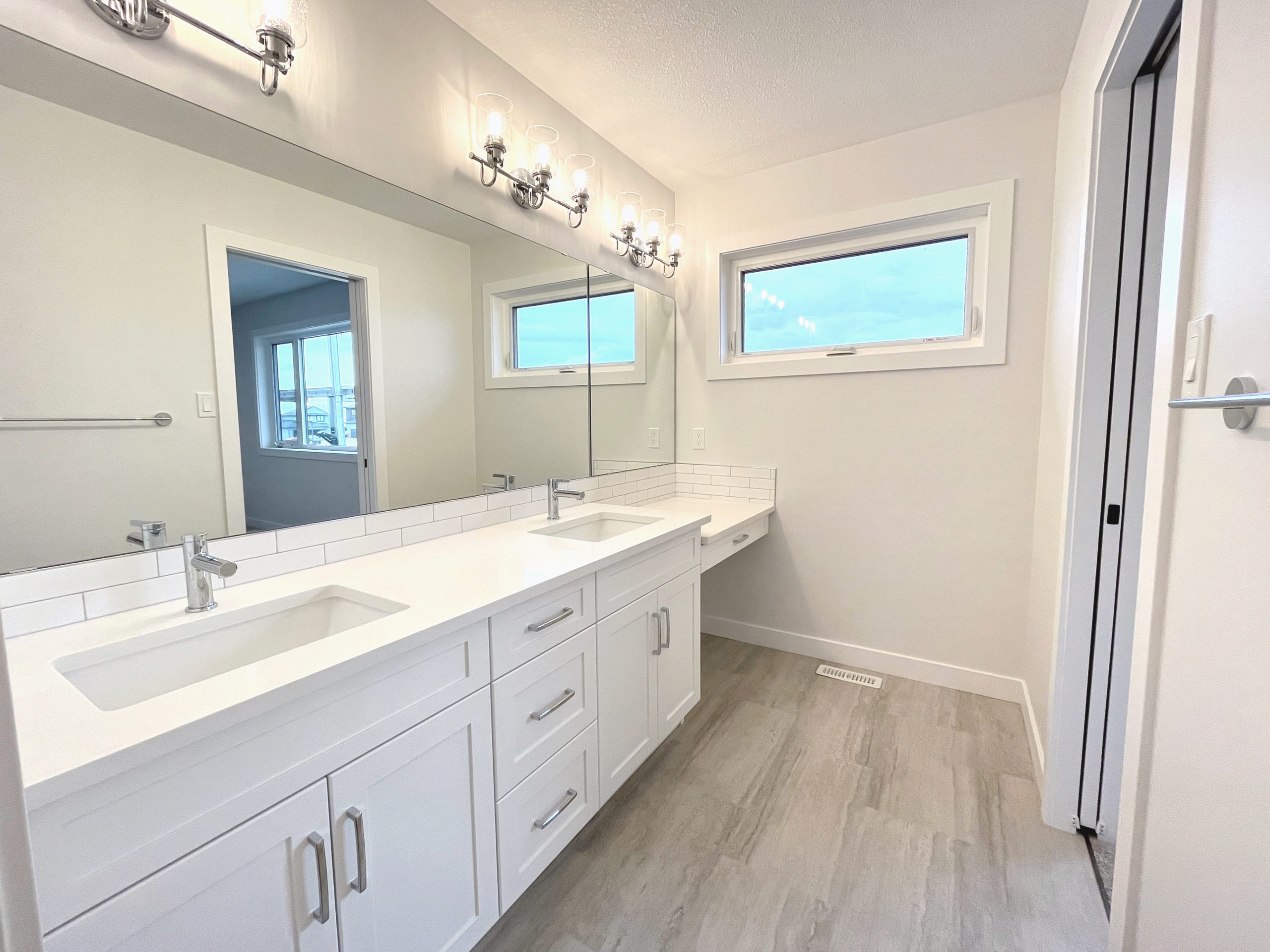 Primary bathroom with a double sink, makeup counter and a large mirror.