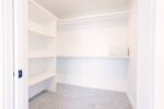 A white closet with shelves and a door.
