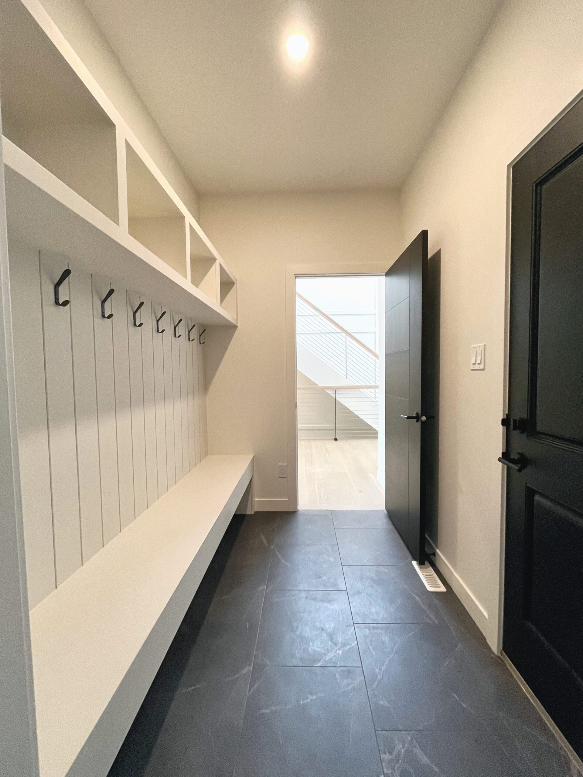 The mudroom with a black door and white shelves.