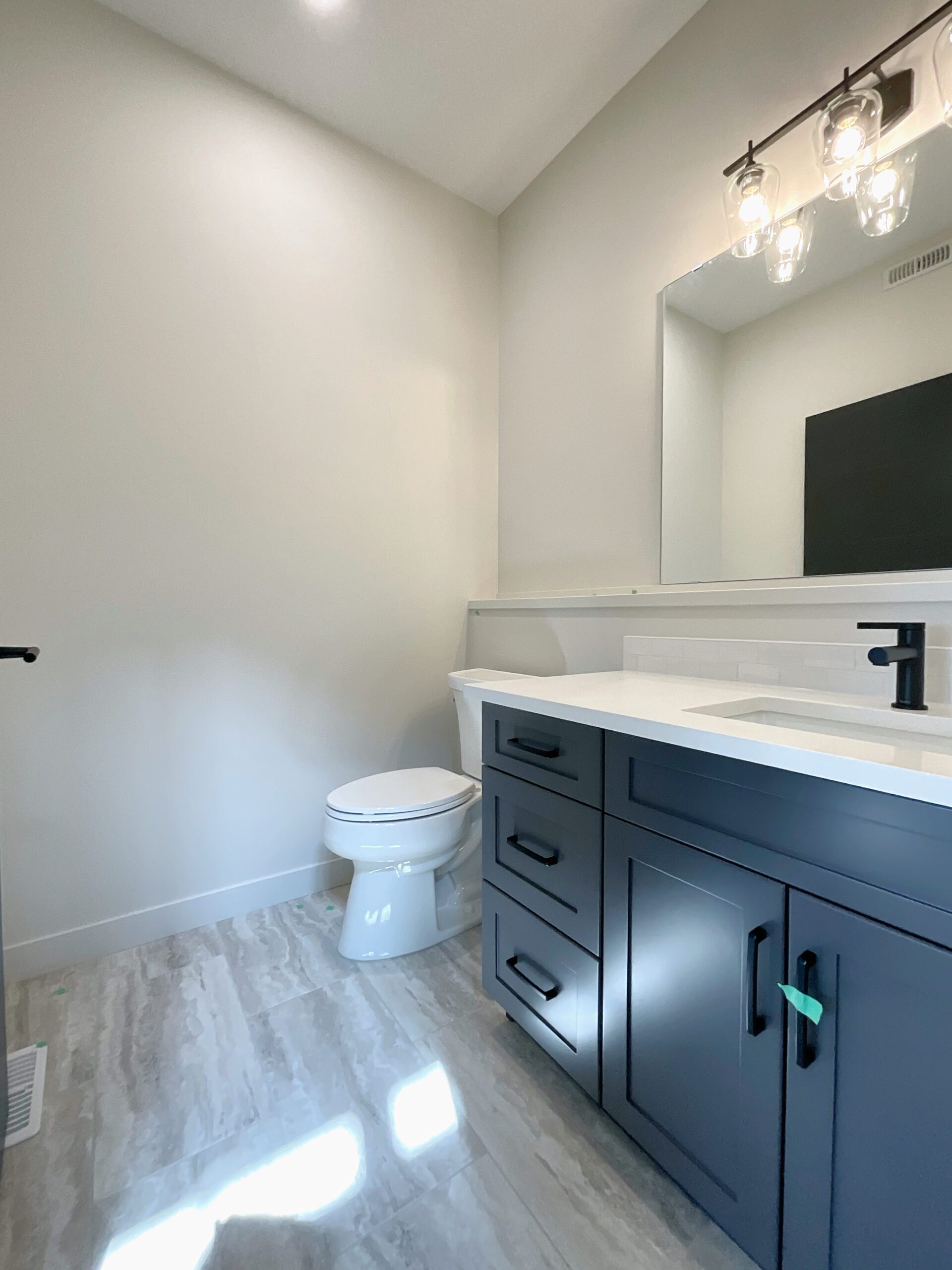 A main floor powder room with white toilet sitting next to a bathroom sink.