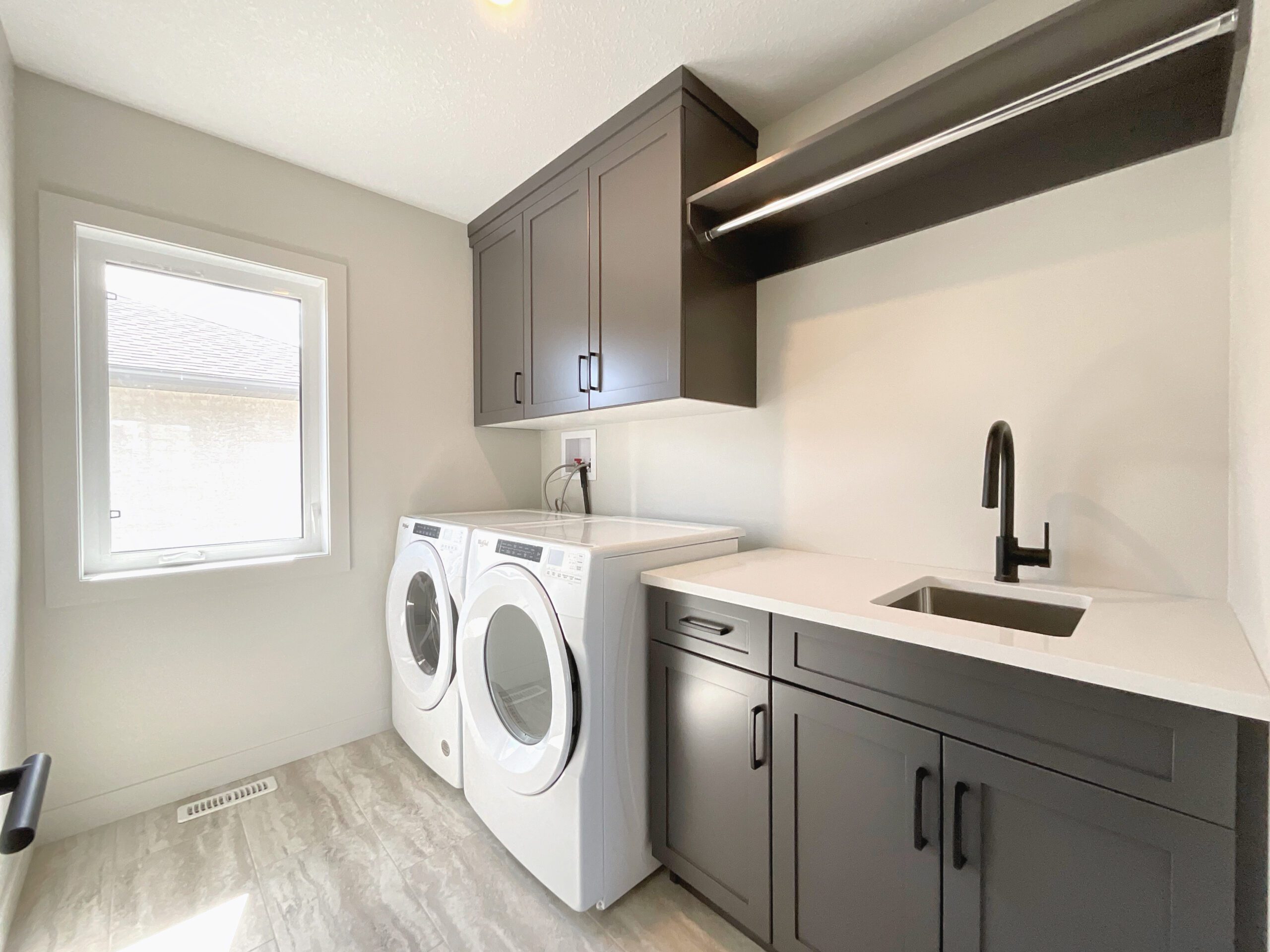 A laundry room with a side-by-side front-load washer and dryer and sink.