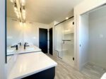 A primary bathroom with a large mirror, double sinks and walk-in shower.