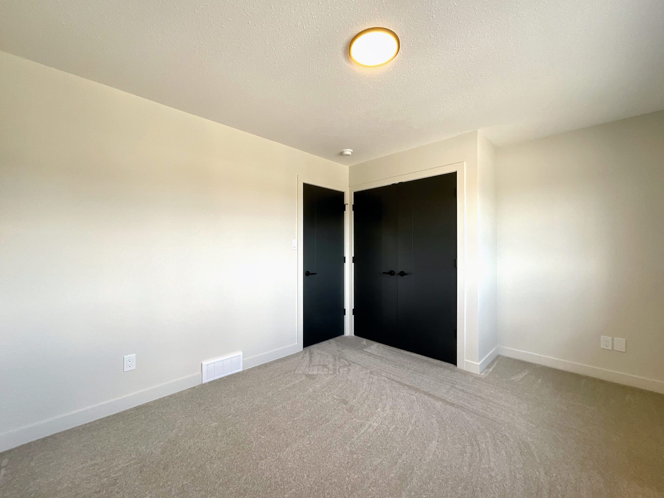 An empty bedroom with black doors and white walls.