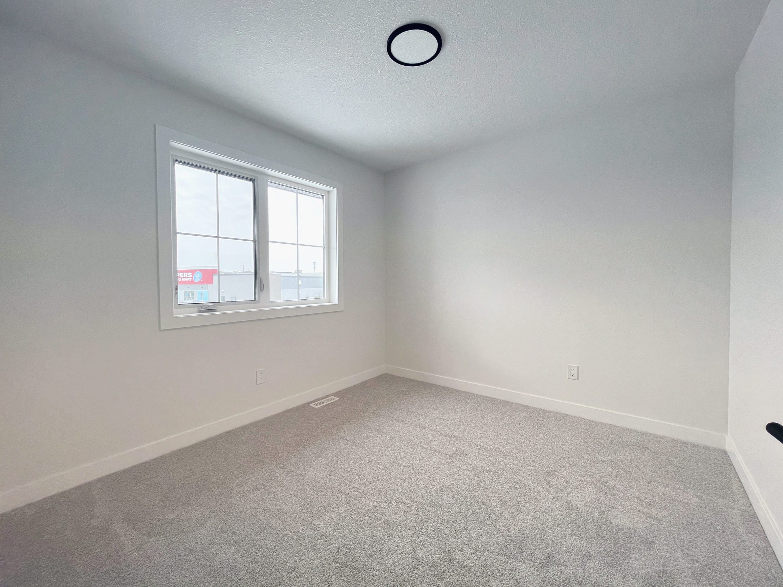 An empty bedroom with white walls and window.