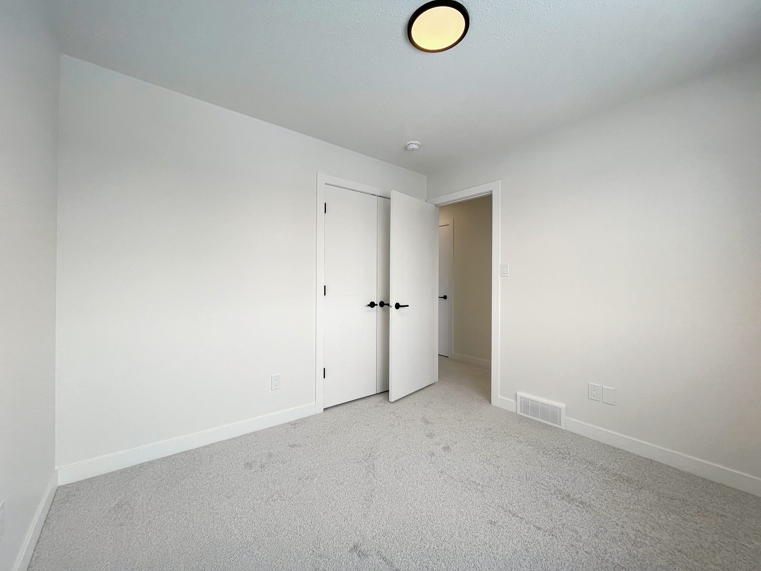 An empty bedroom with white walls and doors.