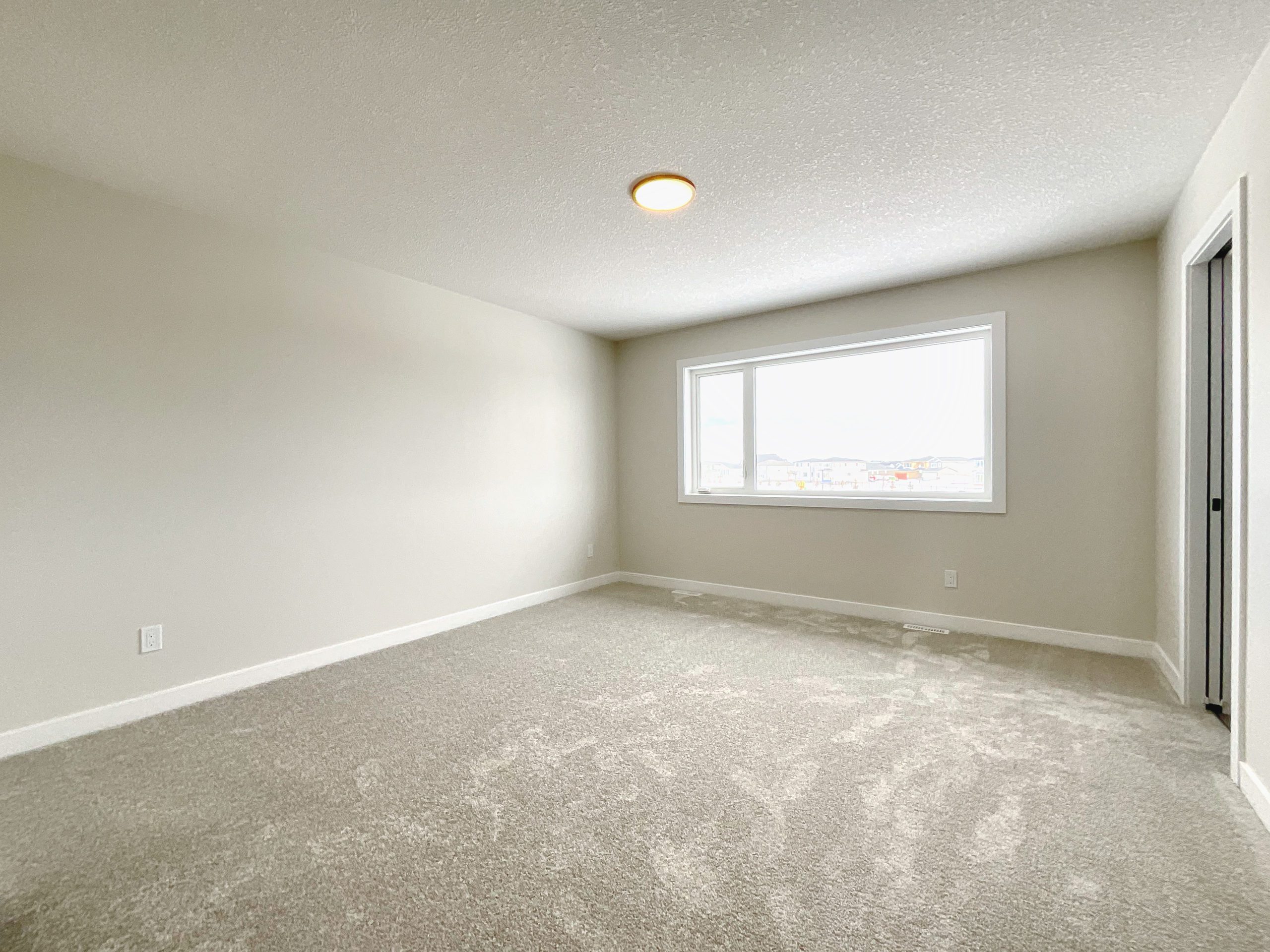 Shows empty primary bedroom with large window.