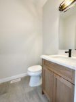 Shows the main floor powder room with white toilet next to vanity.