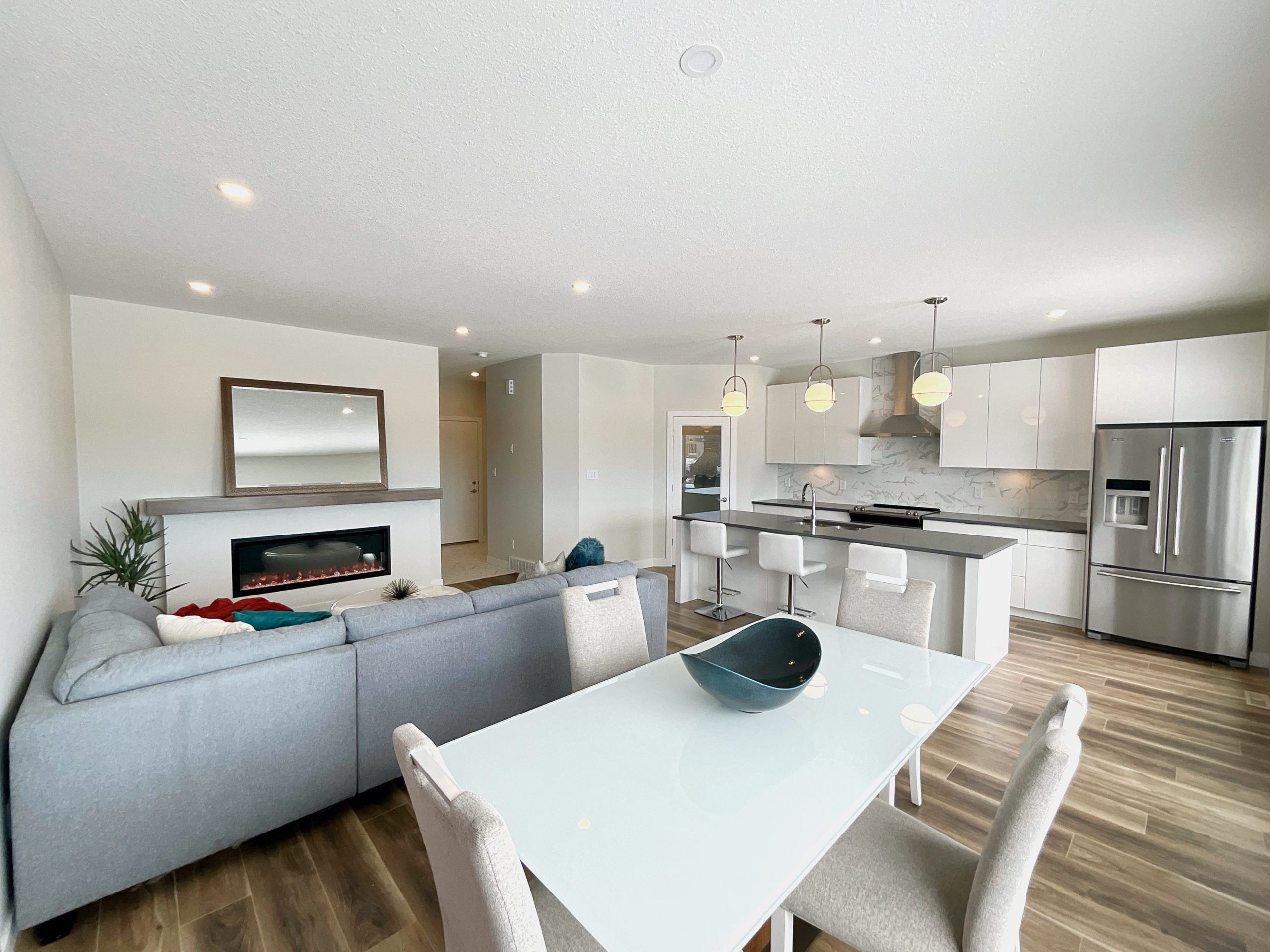 A modern townhome with a white glass table in the open concept living area looking over the kitchen and living room.