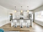Shows the modern kitchen with a center island and three counter height stools.