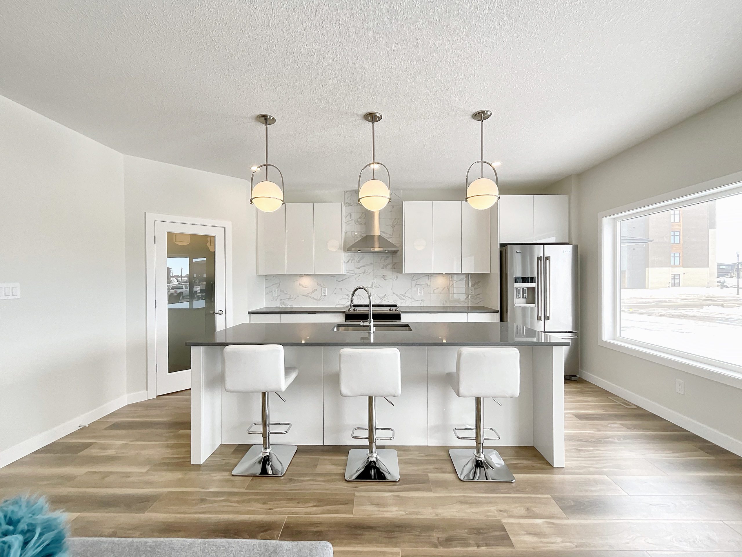 Shows the modern kitchen with a center island and three counter height stools.