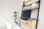 A desk with a wooden shelf and a chair.