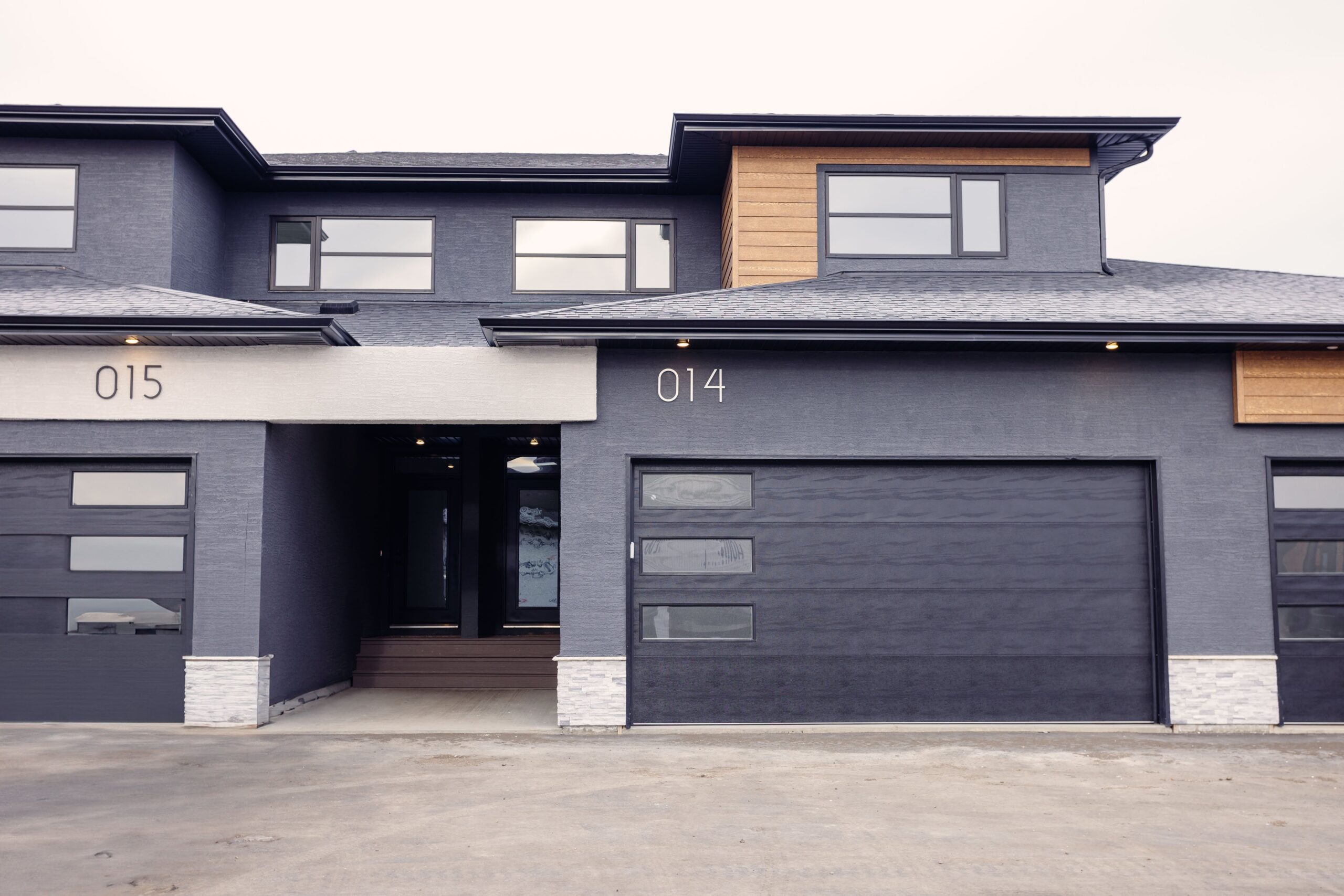 A grey and black house with garage doors.