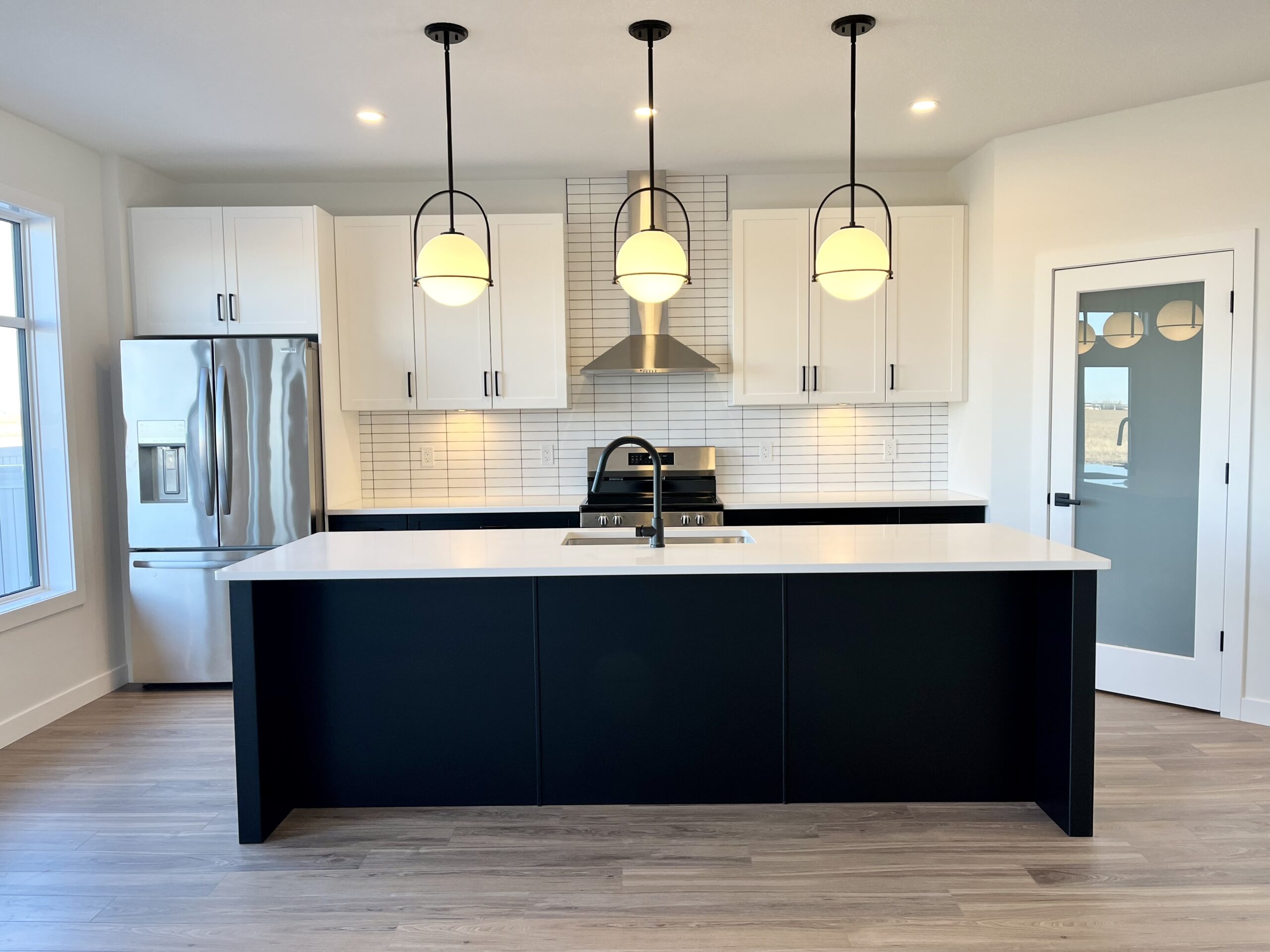 A kitchen with white cabinets and black counter tops.
