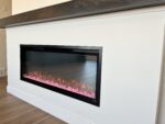 A fireplace with pink rocks on the side.