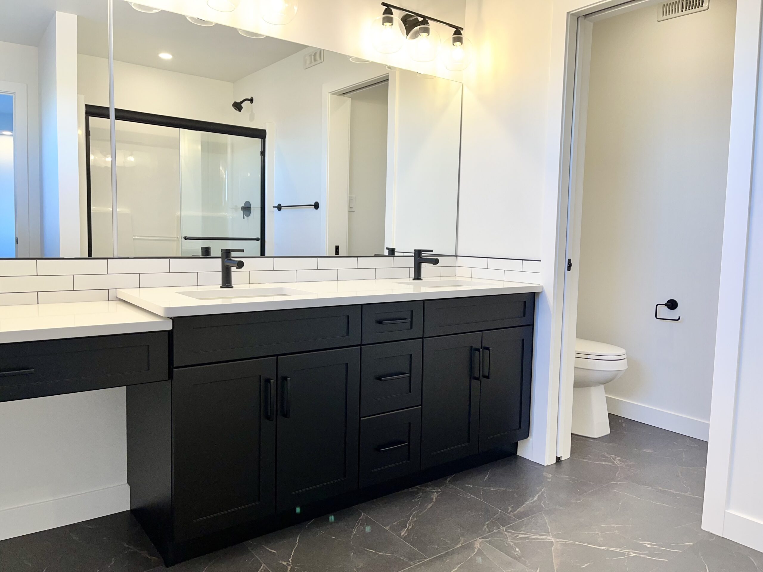 A black and white bathroom with two sinks and a mirror.