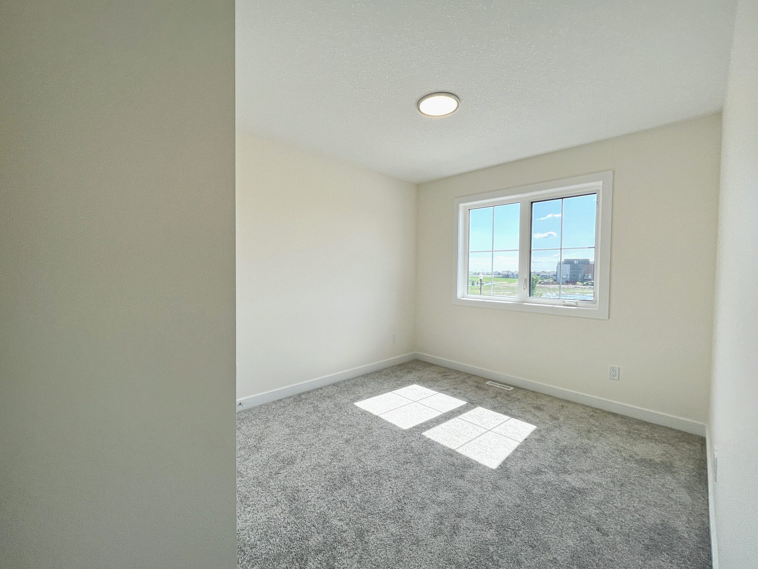 an empty room with a window and carpeted floor.
