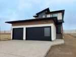 Modern two-storey home in Pilot Butte with a dark exterior and attached double garage.