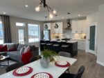 Modern open-concept living space in a two-storey home in Pilot Butte with a kitchen island, dining area, and living room.