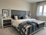 Modern two-storey home in Pilot Butte with a neatly made bed, matching nightstands, and coordinating wall art.