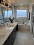 Modern bathroom interior in a two-storey home in Pilot Butte, featuring double vanity and large bathtub, neutral colors, and natural light.