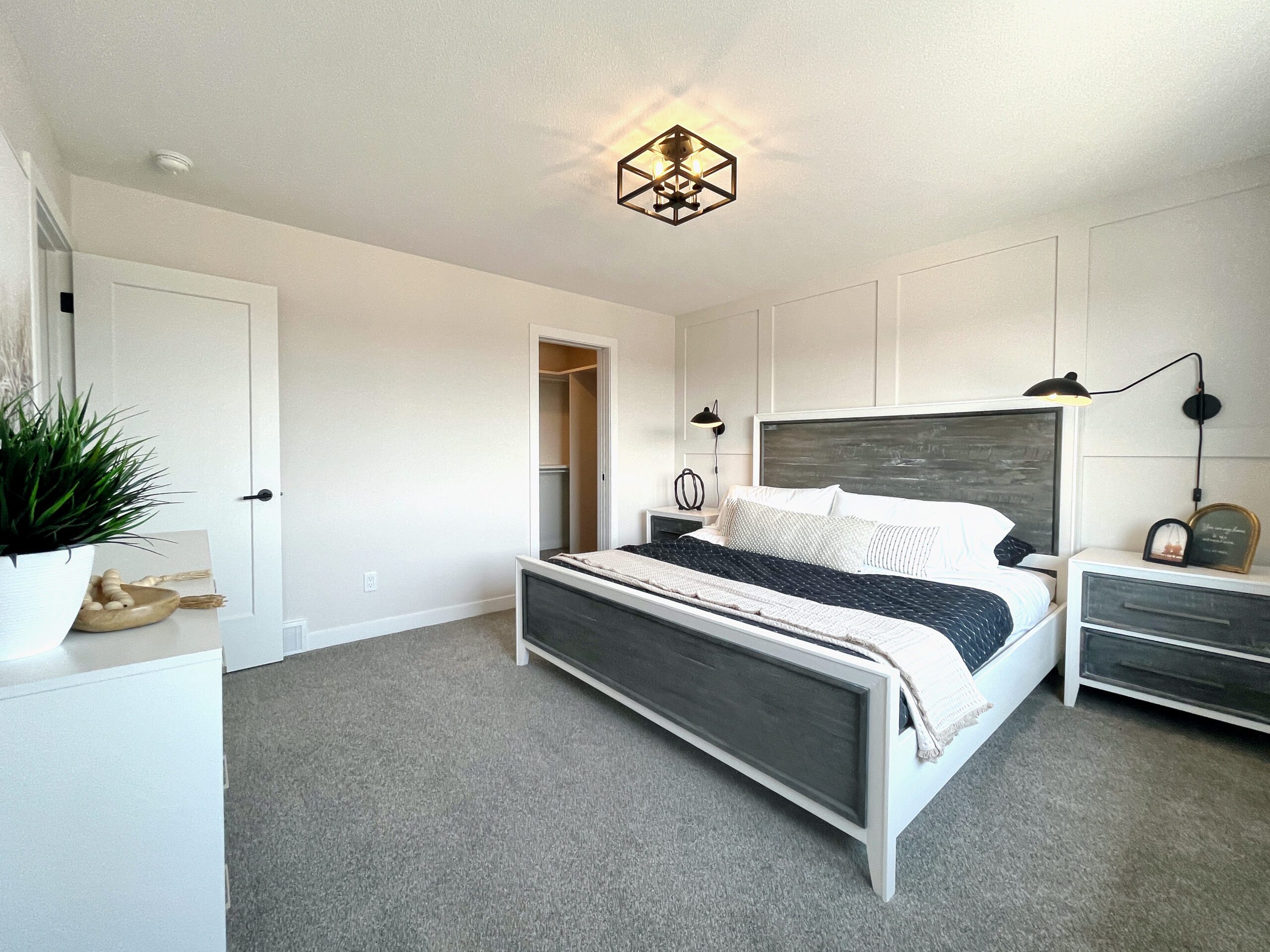 A two-storey home in Pilot Butte with a white bed and gray carpet.