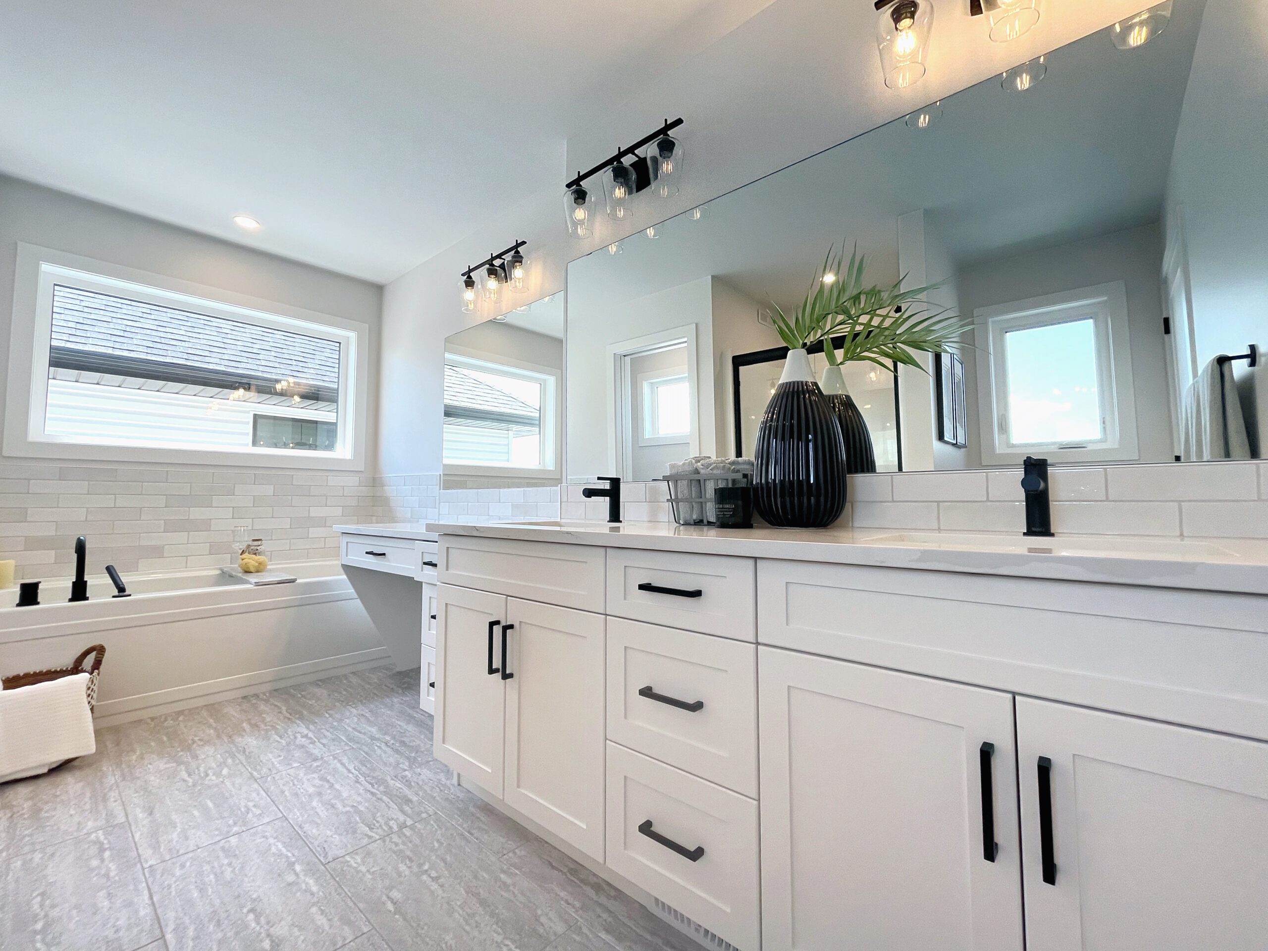 A white bathroom with two sinks and a tub in a two-storey home in Pilot Butte.