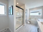 A two-storey home in Pilot Butte, featuring a white bathroom with a walk-in shower.