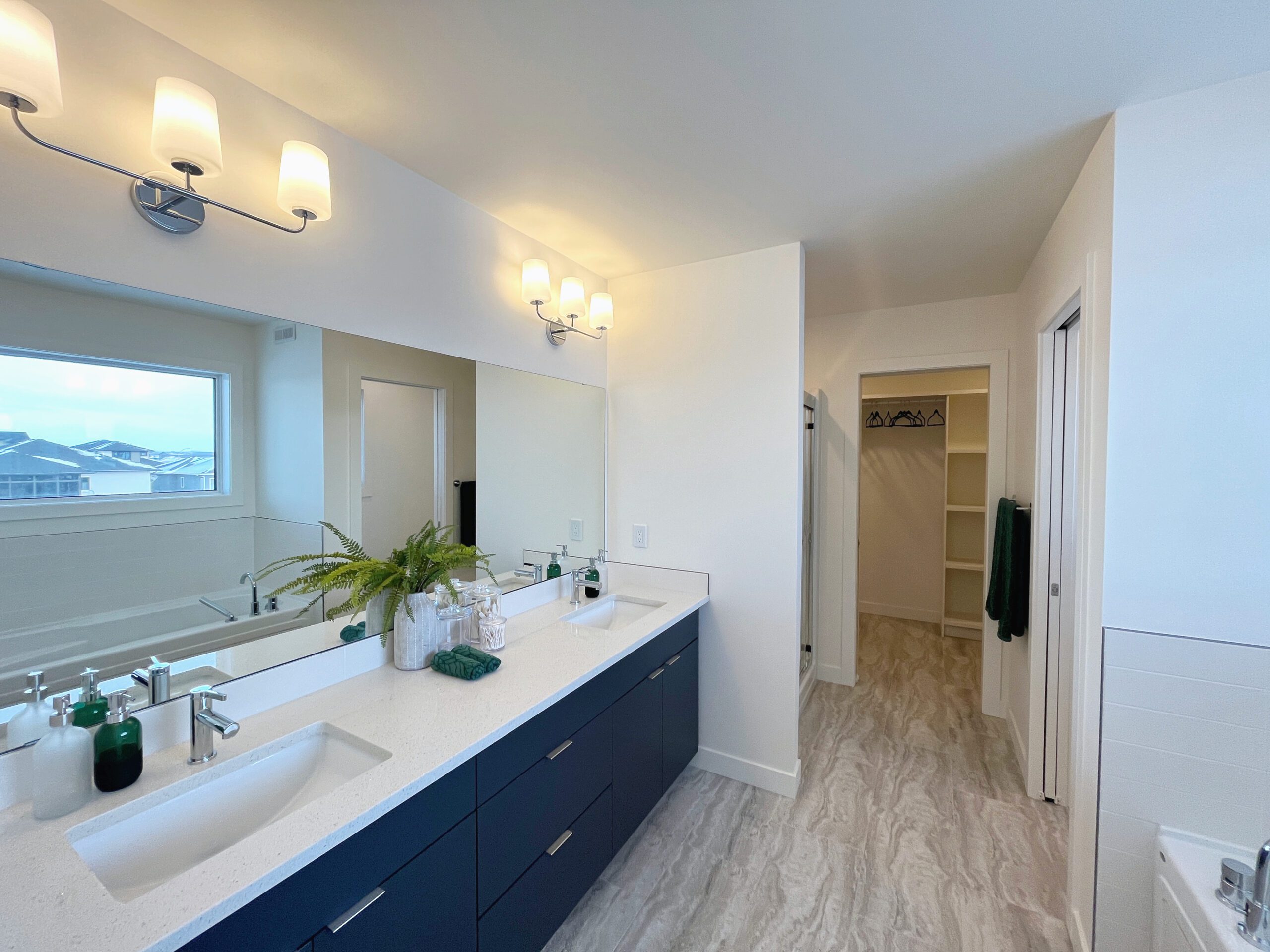 A spacious bathroom with a large mirror and two sinks, located in a luxurious two-storey home in Pilot Butte.