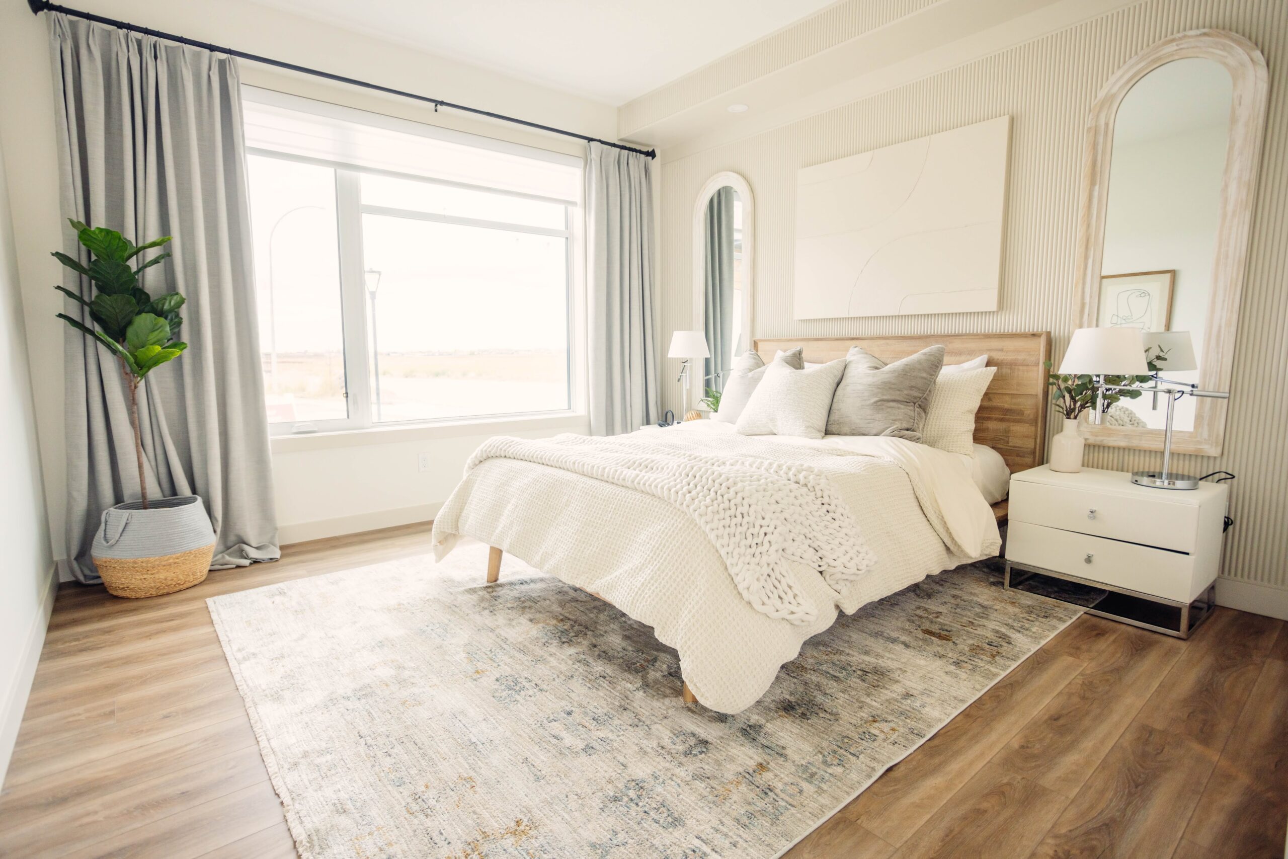 A bedroom with wooden floors and a white bed.