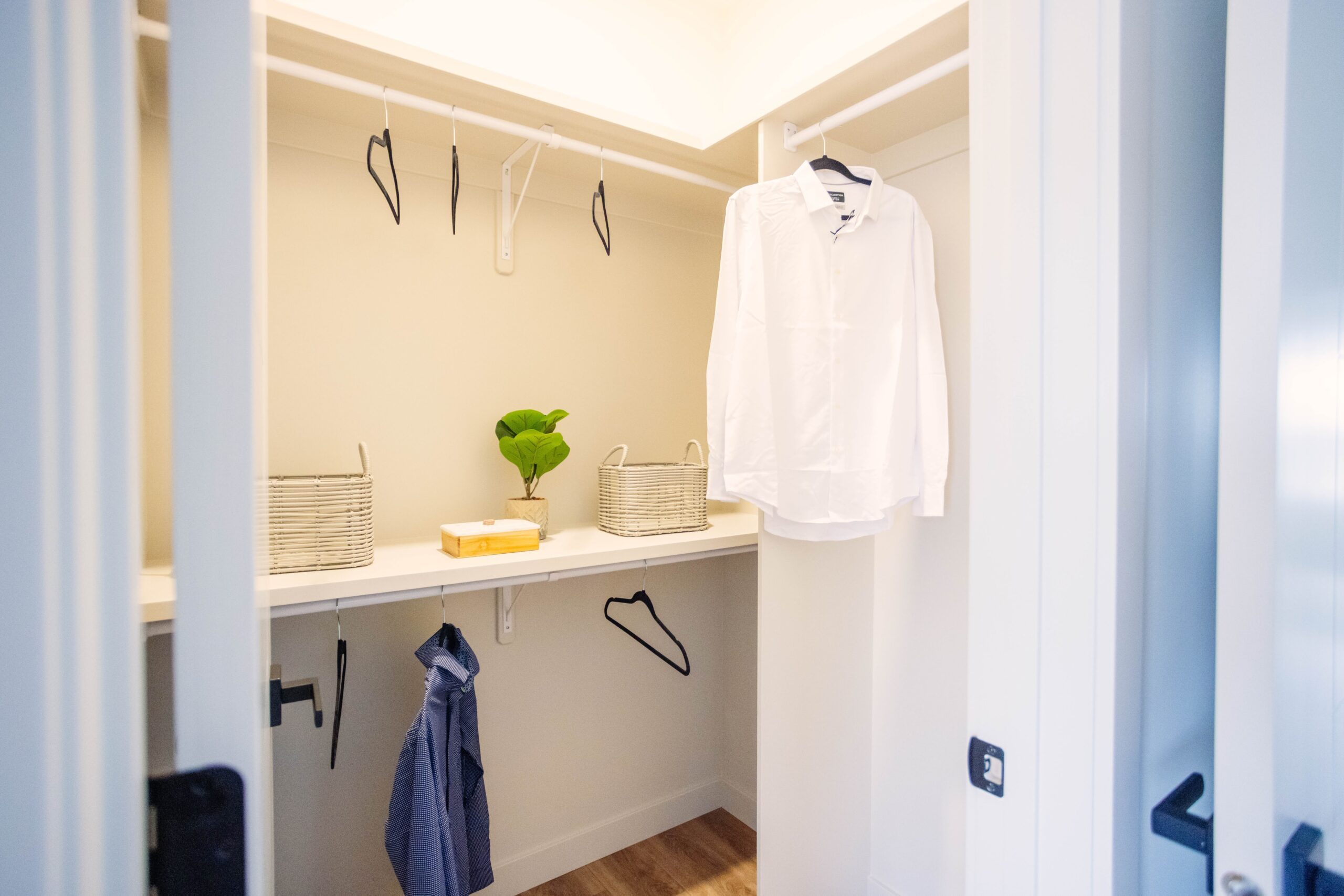 A closet with a white shirt hanging on a hanger.
