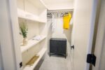 A white closet with shelves and a yellow shirt.