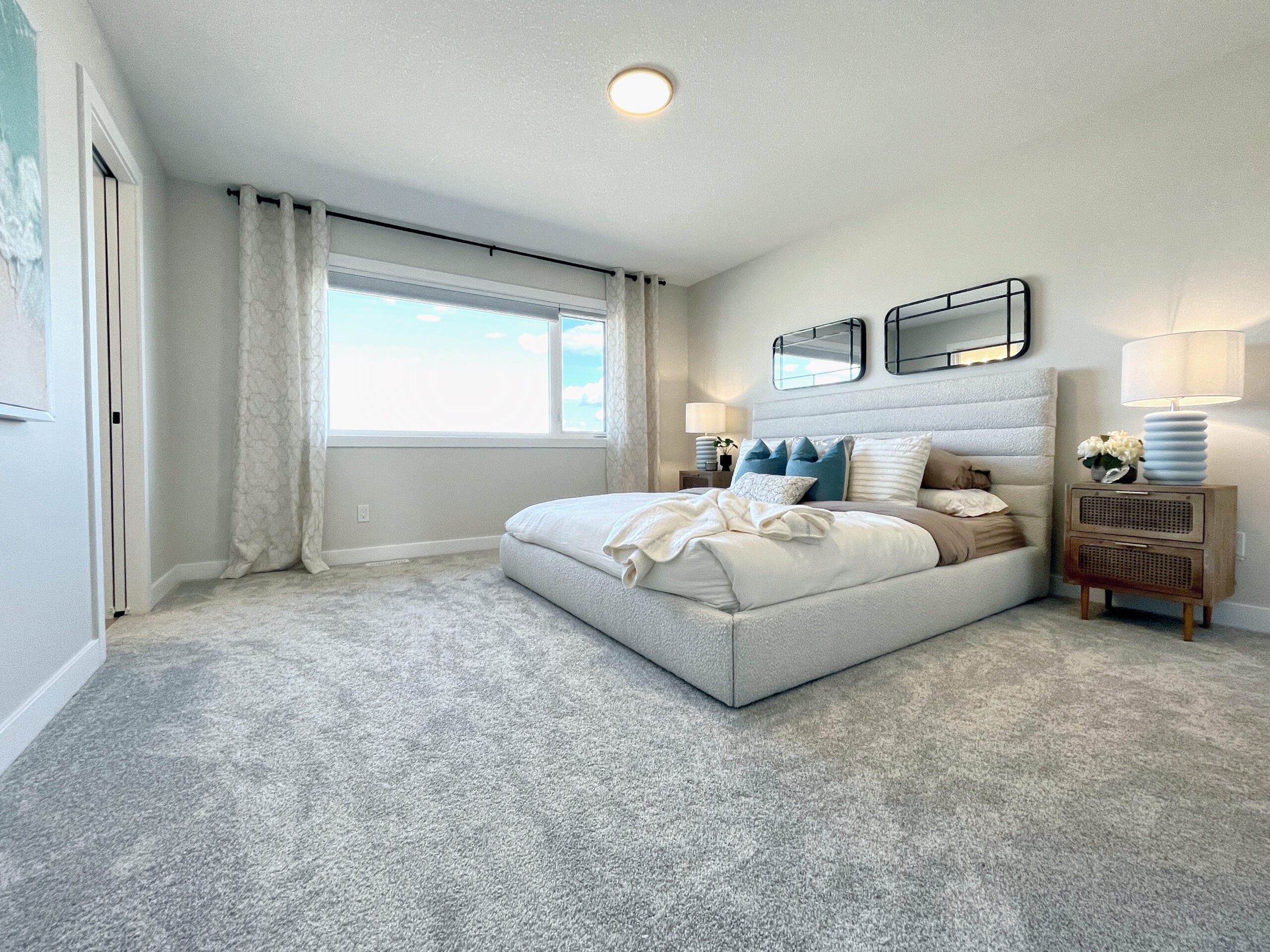 A bedroom with gray carpet and a large bed.