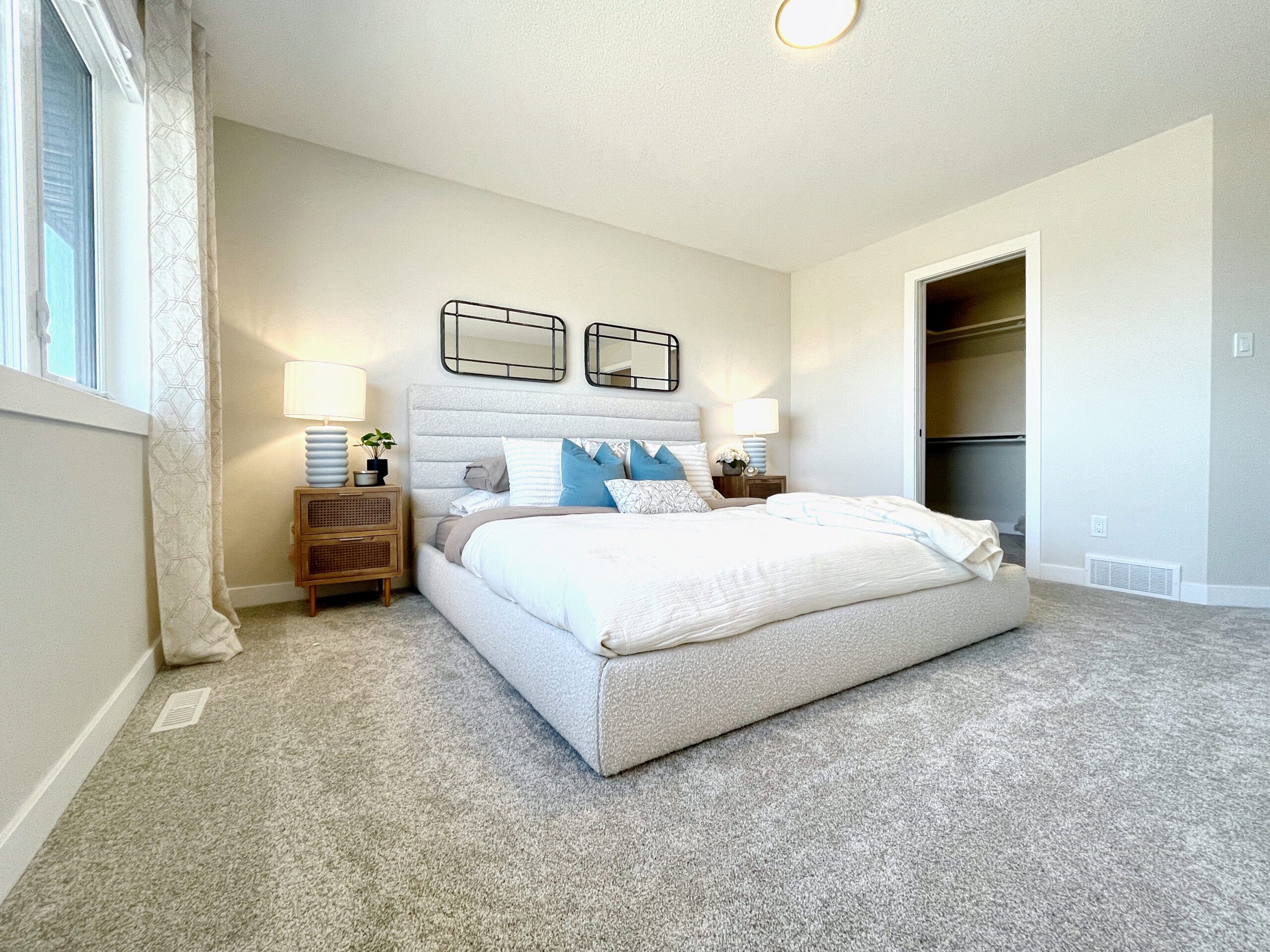 A bedroom with a white bed and gray carpet.