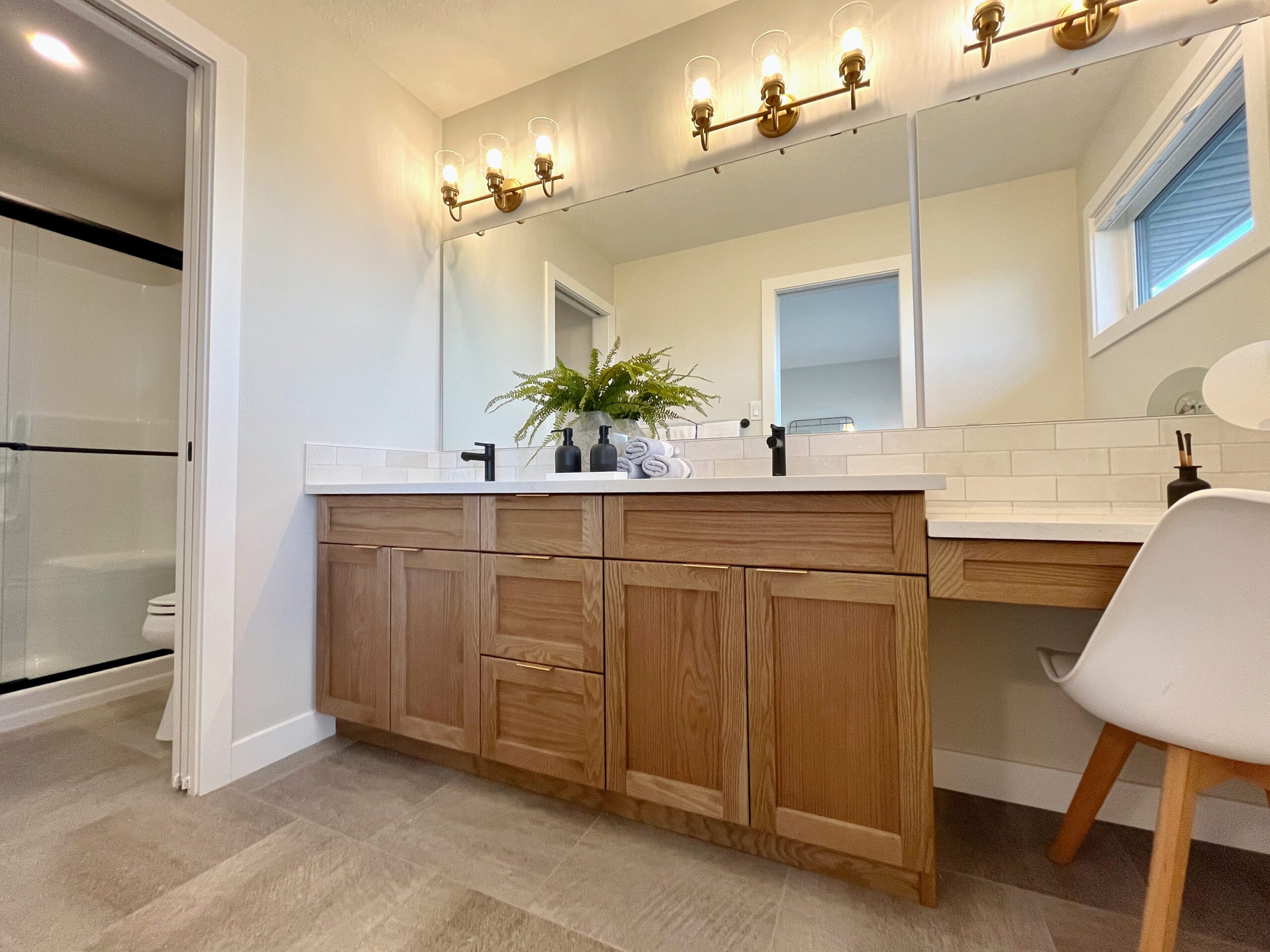 A white bathroom with wooden cabinets and a mirror.