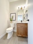 A white bathroom with wood cabinets and a toilet.