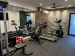 A gym room with exercise equipment and mirrors.