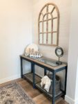 A console table with a mirror and a rug.