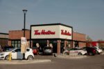 A Tim Hortons restaurant with several cars parked in the lot on a clear day.