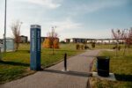 Pathway in Hopson Park with trees and buildings in the background under a clear blue sky.